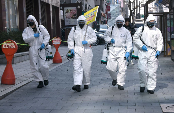 South Korean soldiers wearing protective gear spray disinfectant on the street to help prevent the spread of the COVID-19 coronavirus, at Gangnam district in Seoul on March 5, 2020.