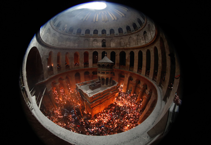 Christian Orthodox worshipers hold up candles lit from the Holy Fire as they gather in the Church of the Holy Sepulchre in Jerusalem's Old City on April 27, 2019, during the Orthodox Easter.