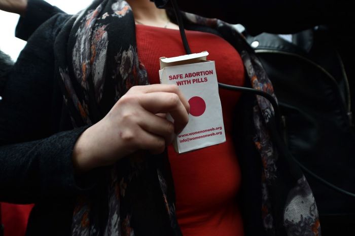 An unidentified woman displays an abortion pill packet after taking one of the pills as abortion rights campaign group ROSA, Reproductive Rights Against Oppression, Sexism and Austerity distribute abortion pills from a touring bus on May 31, 2018 in Belfast, Northern Ireland.