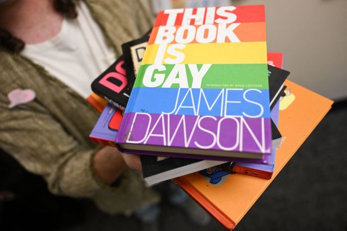 Laramie Pridefest board member Tyler Wolfgang displays a stack of books, some of which have been banned across the U.S. due to controversy, including 'This Book is Gay,' in their office on the University of Wyoming campus in Laramie, Wyoming, on August 13, 2022.