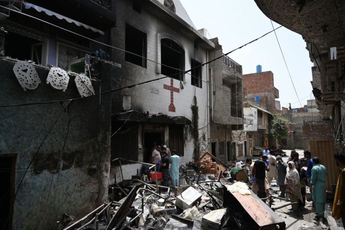 Police officials and residents stand amid debris outside the torched Saint John Church in Jaranwala on the outskirts of Faisalabad on August 17, 2023, a day after an attack by Muslim men following the spread of false accusations that Christians had desecrated a copy of the Quran, the Islamic holy book. Police were guarding a Christian neighborhood in central Pakistan on August 17, after hundreds of Muslim men rampaged through its streets setting fire to churches and ransacking homes over accusations of blasphemy a day earlier.