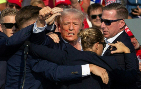 Republican candidate Donald Trump is seen with blood on his face surrounded by secret service agents as he is taken off the stage at a campaign event at Butler Farm Show Inc. in Butler, Pennsylvania, July 13, 2024. The suspected shooter who wounded Republican presidential candidate Donald Trump at a rally is dead, along with one rally attendee who was shot by the shooter.