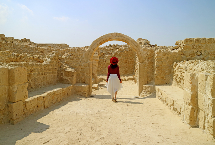 A woman stands at the Bahrain Fort or Qal'at al-Bahrain, a UNESCO World Heritage Site in Manama, Bahrain.